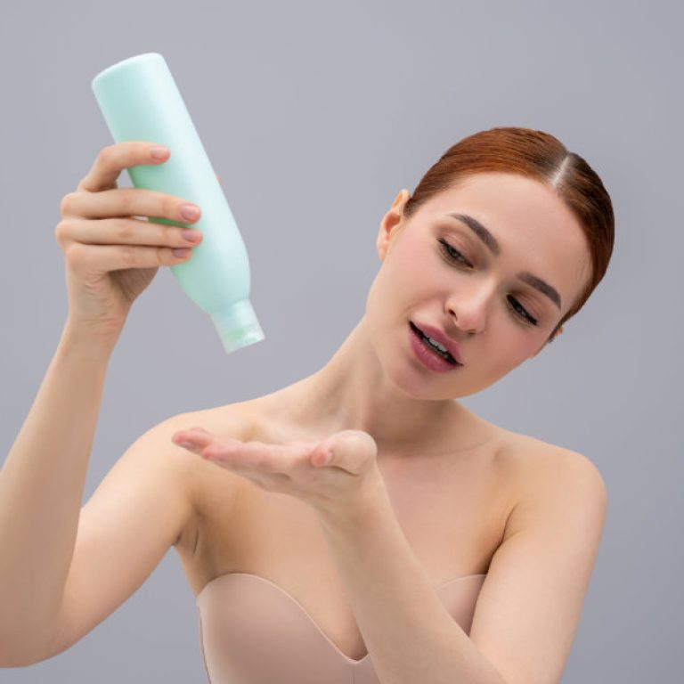 Hair care. Young ginger woman using anti-dandruff shampoo while washing her hair